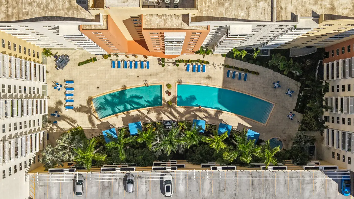 Overhead view of the curved pools and palm-lined pool deck at The Venture at Aventura